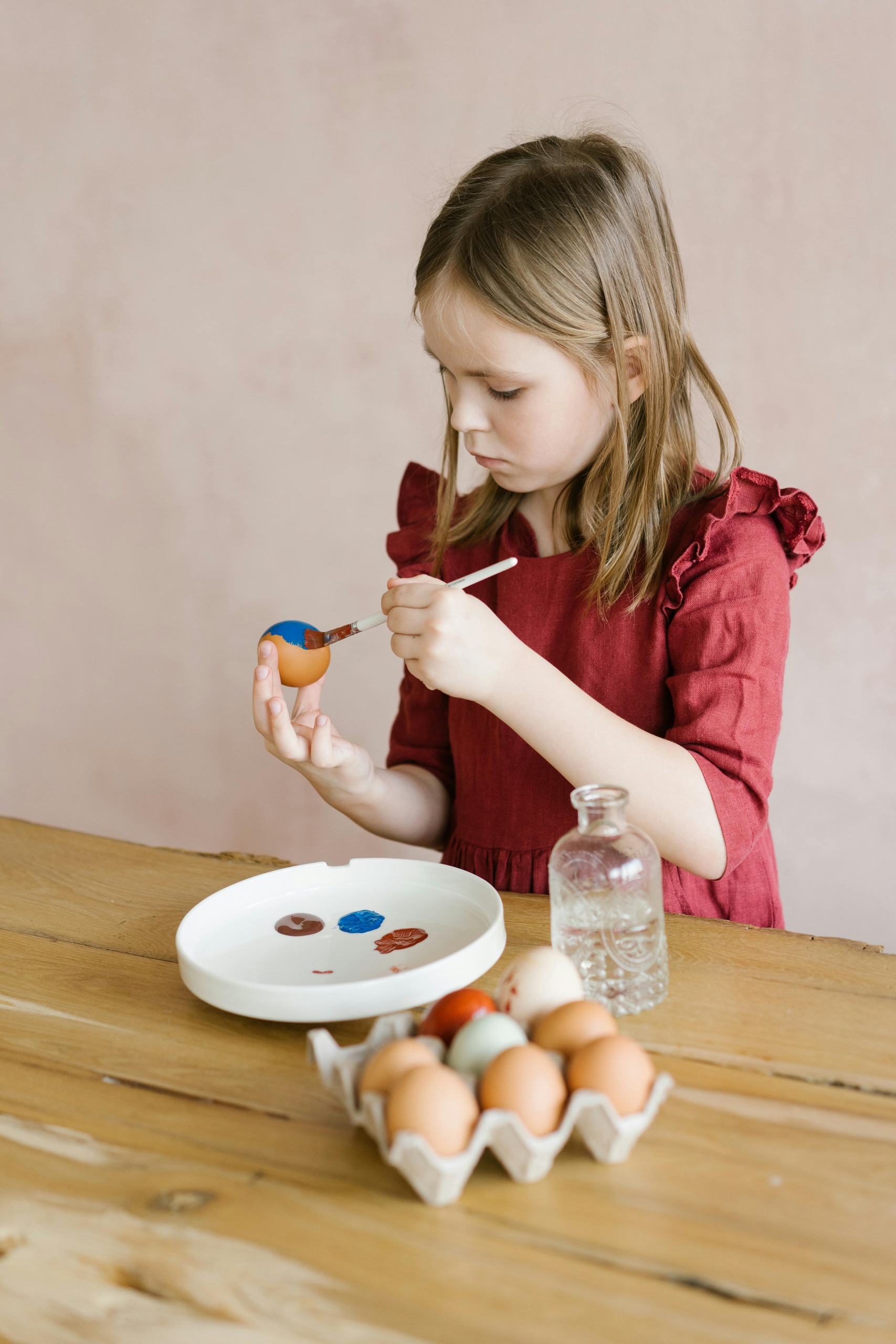Child painting eggs at a table with art supplies.