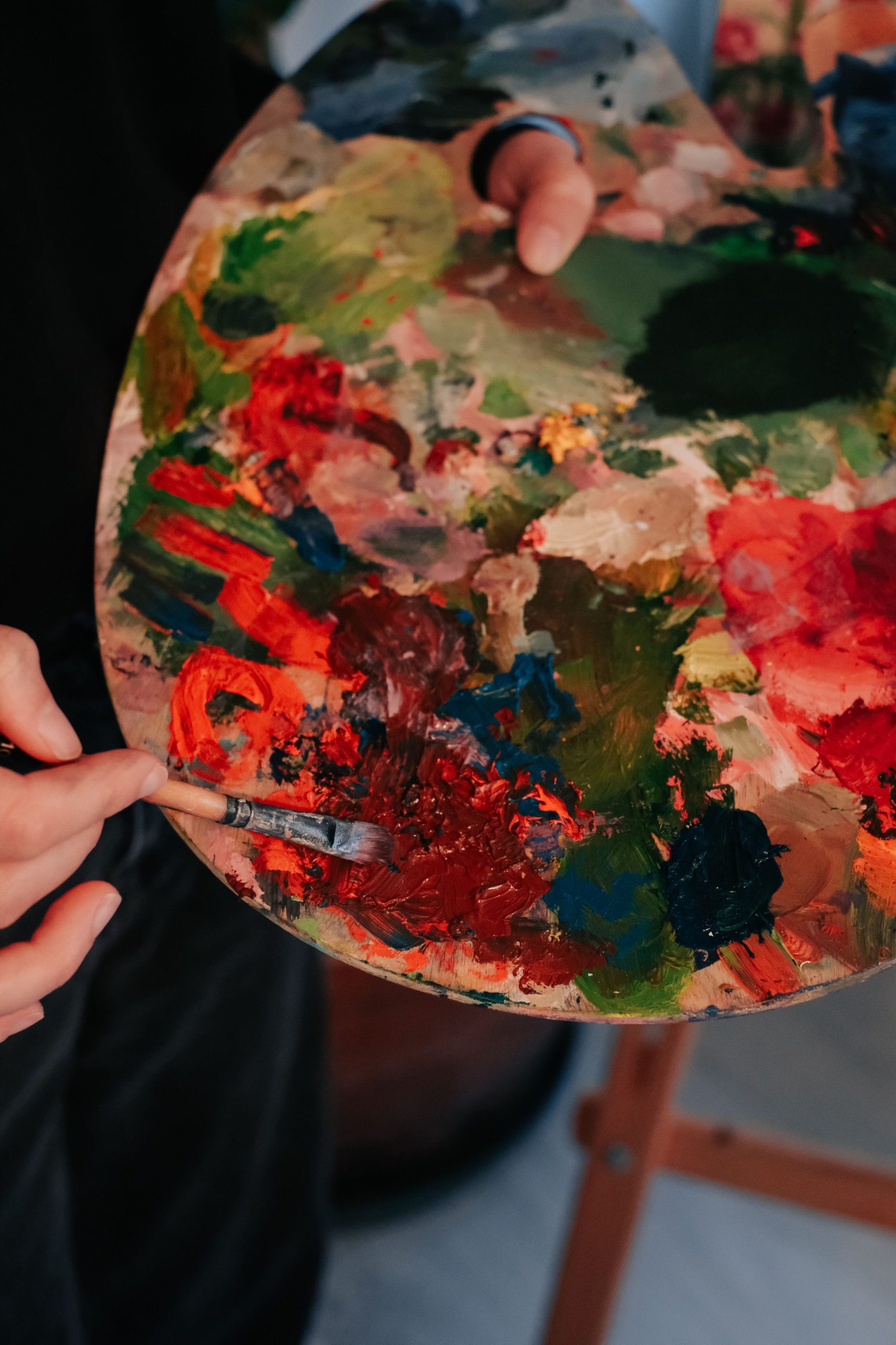 Artist mixing vibrant paints on a palette with a brush.